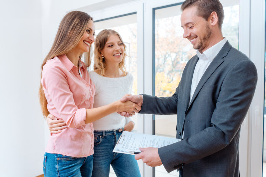 Property manager shaking hands with two women tenants